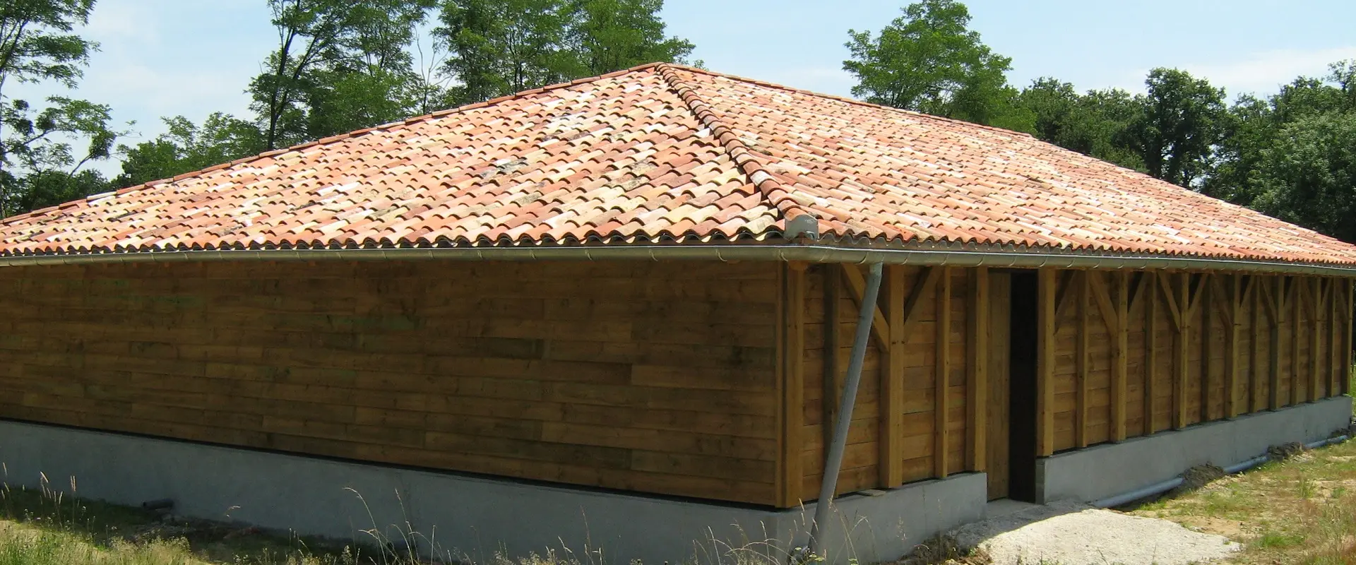 Bâtiment à bardage bois achevé et couverture en tuile canal, vu depuis la toiture