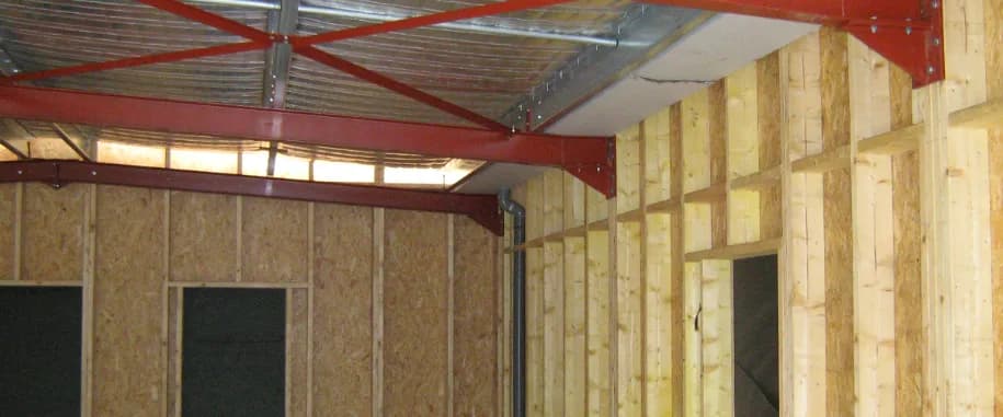 Intérieur d'une maison à ossature bois en cours de montage, montants, panneaux OSB et poutres métalliques apparents